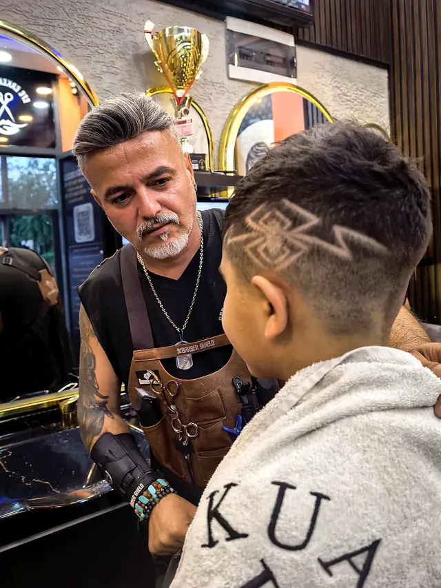 Efe Erkek Kuaförü'nün vitrin tarafından salon içi: deri bekleme koltuğu, berber koltukları ve taş desenli tavan